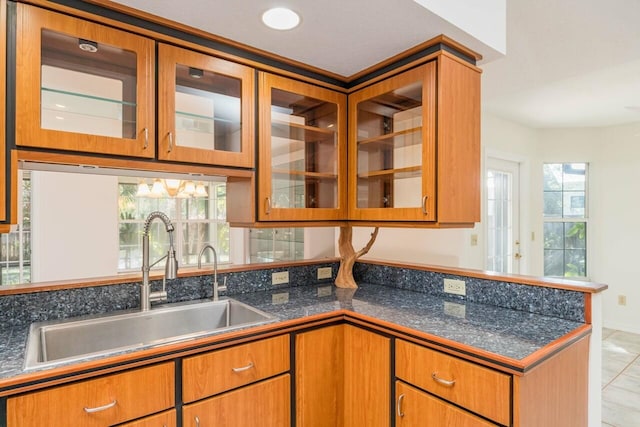 kitchen featuring a sink, glass insert cabinets, and brown cabinets