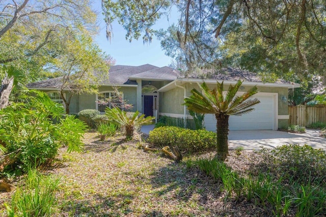 ranch-style house featuring concrete driveway, an attached garage, fence, and stucco siding