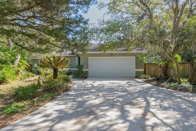 view of front of home featuring an attached garage, fence, concrete driveway, and stucco siding