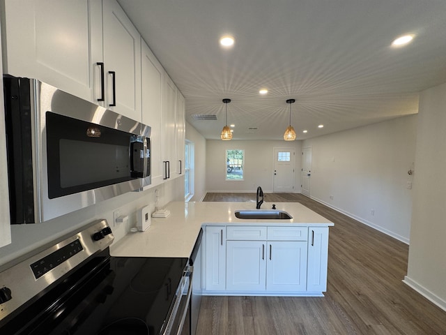 kitchen featuring a sink, stainless steel appliances, a peninsula, and white cabinetry