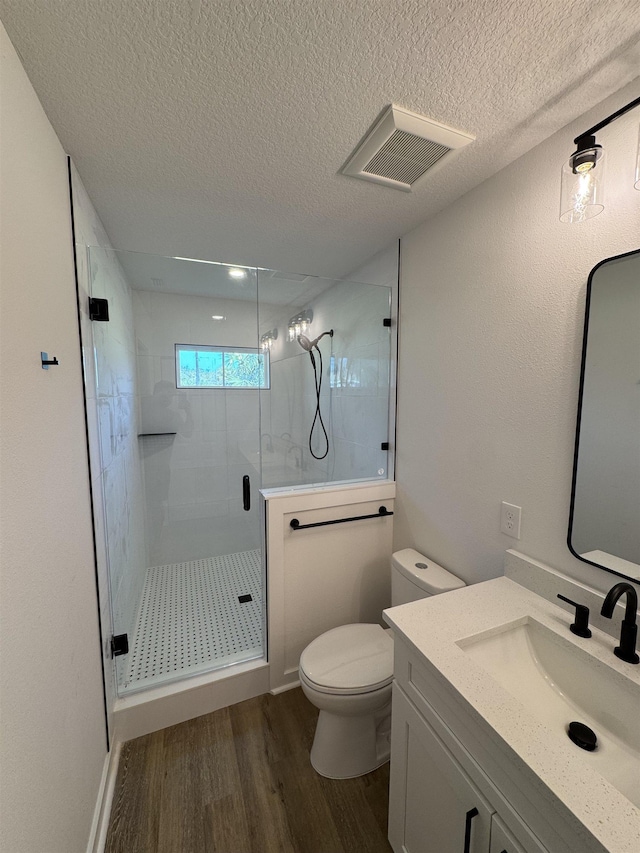 bathroom with wood finished floors, visible vents, a stall shower, a textured ceiling, and toilet