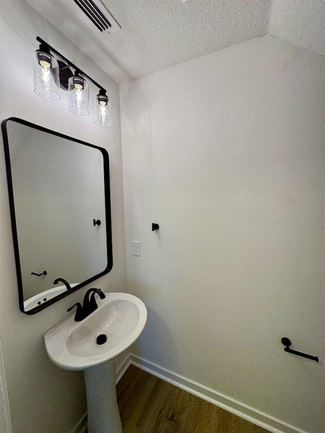 bathroom with visible vents, wood finished floors, baseboards, and a textured ceiling