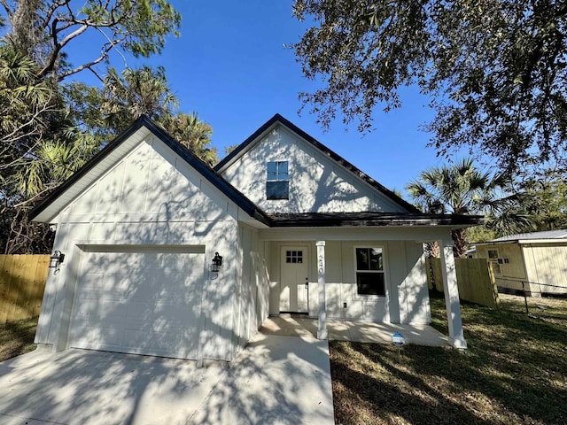 view of front of home featuring a porch, fence, a garage, and driveway