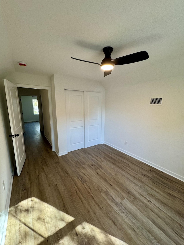 unfurnished bedroom featuring a ceiling fan, wood finished floors, visible vents, baseboards, and a closet