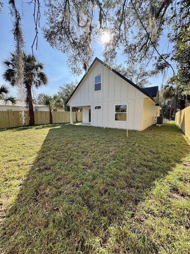 back of house with a yard, cooling unit, board and batten siding, and a fenced backyard