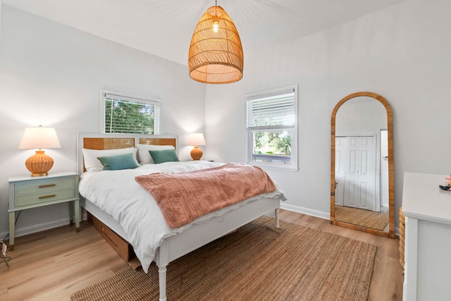 bedroom with light wood-style flooring, multiple windows, and baseboards