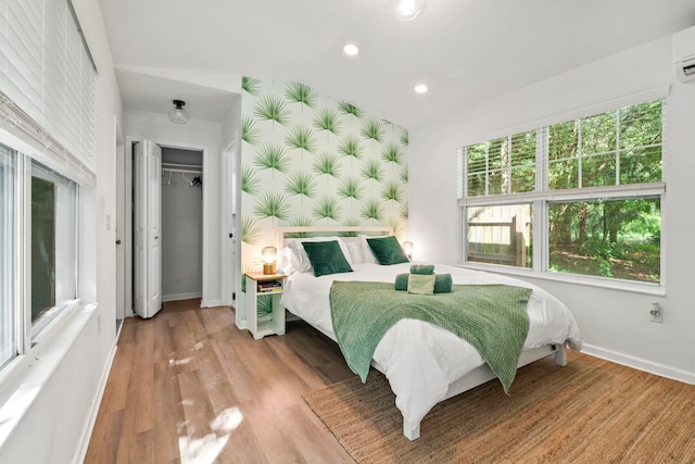 bedroom featuring baseboards, an accent wall, light wood-style floors, recessed lighting, and wallpapered walls