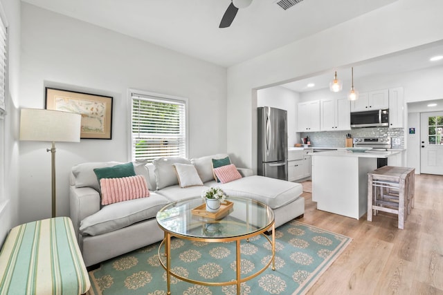 living area featuring light wood-style flooring, ceiling fan, recessed lighting, and a healthy amount of sunlight