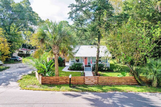 view of front of house featuring a front yard, metal roof, a fenced front yard, and covered porch
