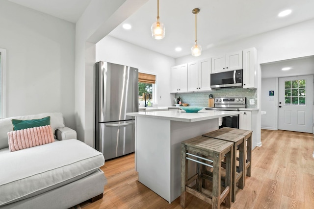 kitchen with a wealth of natural light, tasteful backsplash, white cabinets, and appliances with stainless steel finishes
