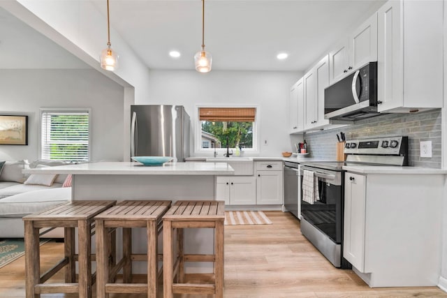 kitchen featuring tasteful backsplash, a breakfast bar, light countertops, white cabinetry, and appliances with stainless steel finishes
