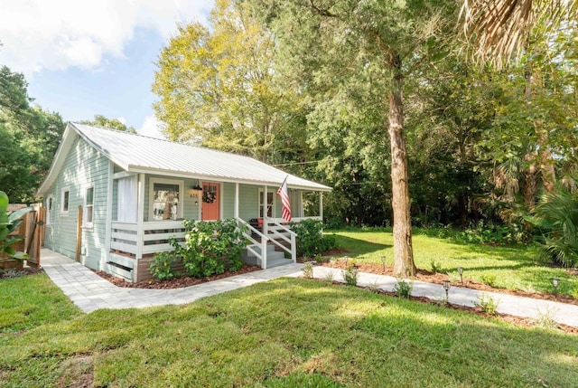 view of front of home featuring covered porch, a front yard, and metal roof