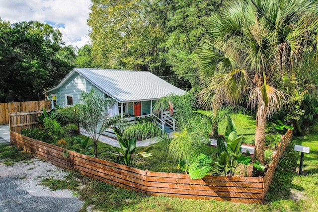 view of front of home featuring metal roof, fence, and a vegetable garden