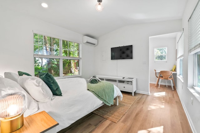 bedroom with multiple windows, lofted ceiling, light wood-style floors, and a wall mounted air conditioner
