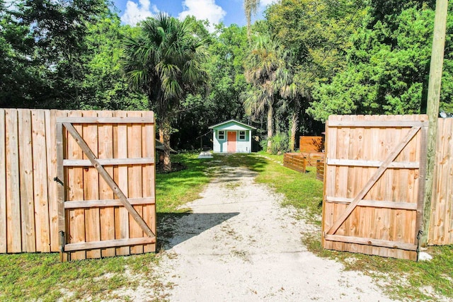 view of gate with an outbuilding and fence