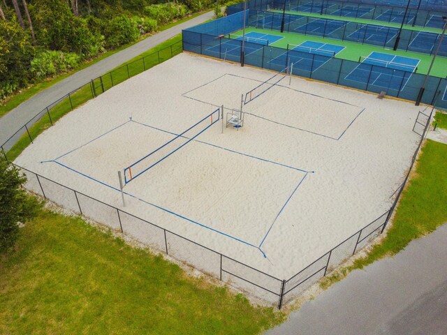 view of property's community featuring a lawn, a tennis court, and fence