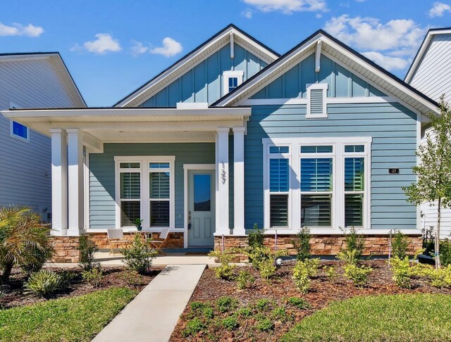 view of front of property featuring a porch, stone siding, and board and batten siding