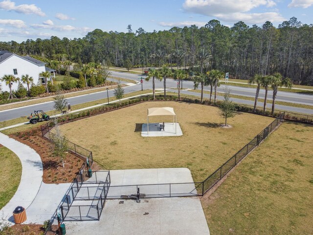 surrounding community with a wooded view, a lawn, and fence