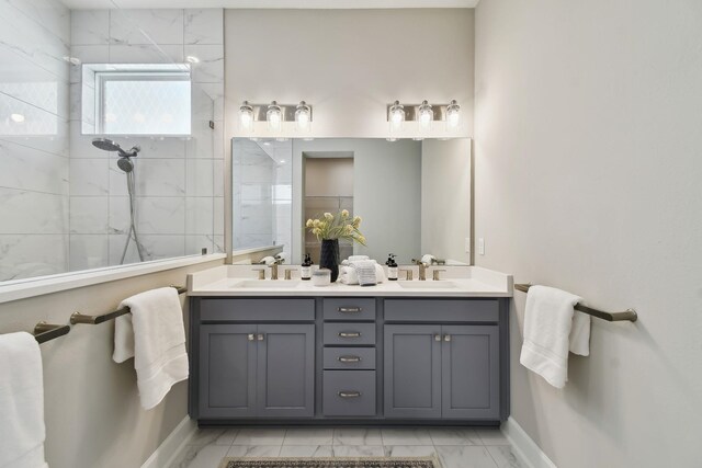 bathroom featuring double vanity, marble finish floor, walk in shower, and a sink