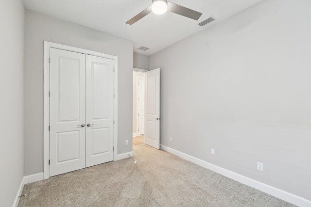 unfurnished bedroom featuring visible vents, a closet, carpet flooring, baseboards, and ceiling fan