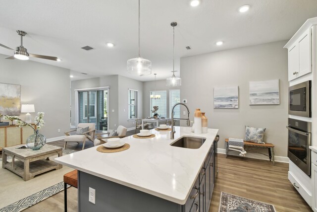 kitchen featuring visible vents, built in microwave, a kitchen bar, stainless steel oven, and a sink