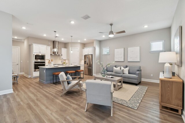 living area featuring a ceiling fan, baseboards, visible vents, recessed lighting, and light wood-type flooring