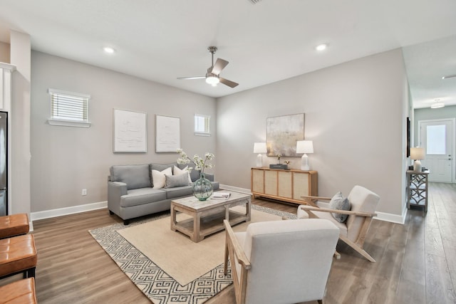 living room with baseboards, plenty of natural light, wood finished floors, and a ceiling fan
