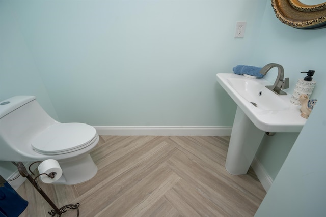 half bath featuring toilet and baseboards