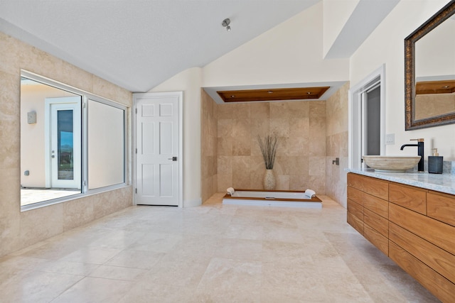 full bathroom featuring lofted ceiling, vanity, and a textured ceiling