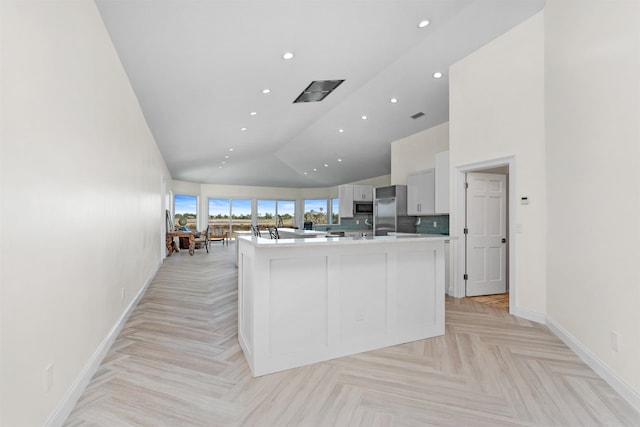 kitchen featuring baseboards, an island with sink, appliances with stainless steel finishes, light countertops, and recessed lighting