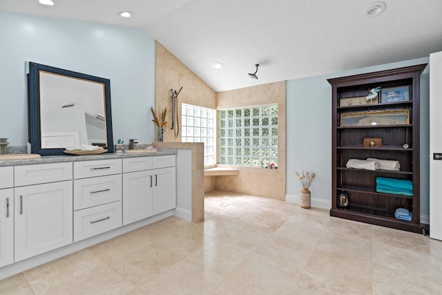 full bathroom featuring double vanity, tile patterned flooring, a bathtub, vaulted ceiling, and a sink