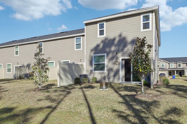 rear view of house featuring central AC and a lawn