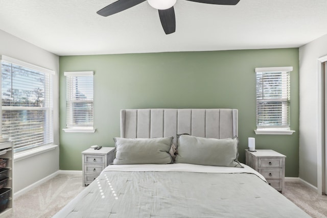 bedroom featuring ceiling fan, light carpet, and a textured ceiling