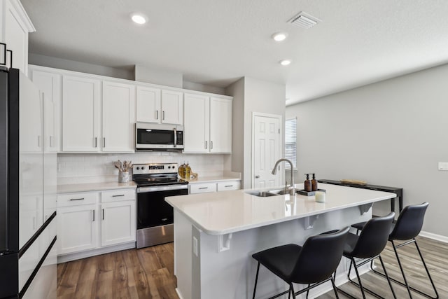 kitchen with a kitchen island with sink, sink, stainless steel appliances, and white cabinets