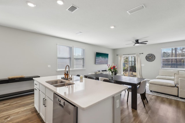 kitchen featuring sink, a center island with sink, stainless steel dishwasher, hardwood / wood-style flooring, and white cabinets