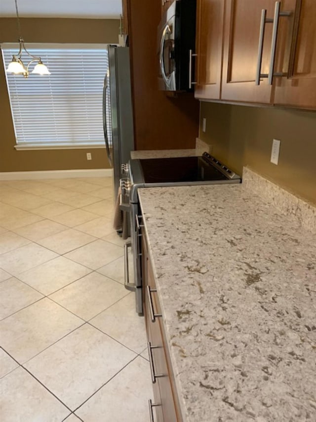 kitchen with light stone countertops, stainless steel appliances, light tile patterned floors, decorative light fixtures, and a notable chandelier