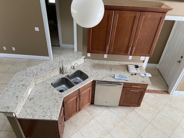 kitchen featuring stainless steel dishwasher, light tile patterned flooring, light stone countertops, and sink