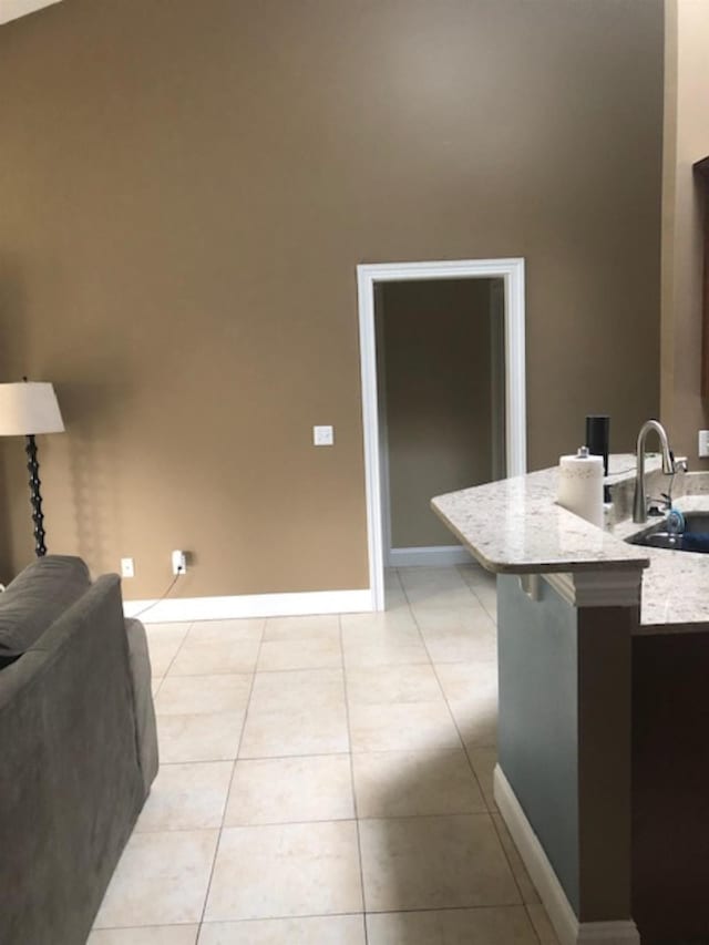 kitchen featuring a kitchen breakfast bar, light tile patterned floors, sink, and vaulted ceiling