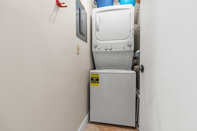 washroom with electric panel, light tile patterned flooring, and stacked washing maching and dryer