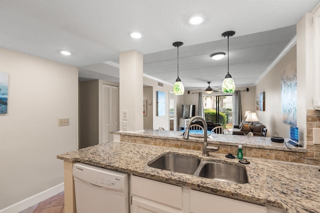 kitchen featuring light stone counters, white dishwasher, sink, decorative light fixtures, and white cabinetry