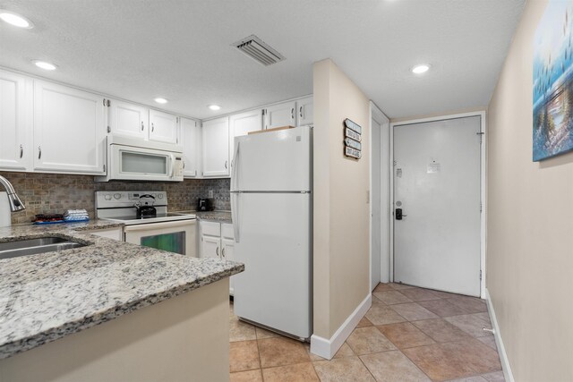 kitchen with white appliances, white cabinets, sink, decorative backsplash, and light stone counters