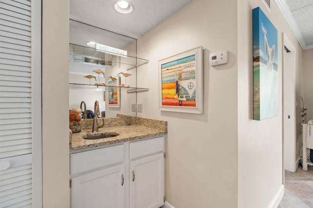 bar with sink, light stone counters, a textured ceiling, white cabinets, and ornamental molding