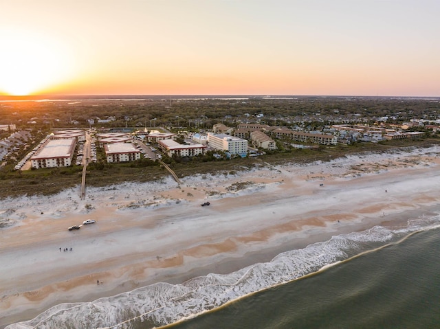 aerial view at dusk with a view of the beach and a water view