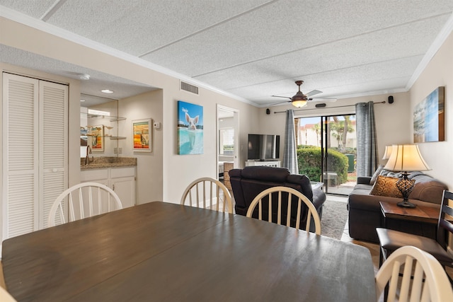 dining area featuring ceiling fan, crown molding, and sink