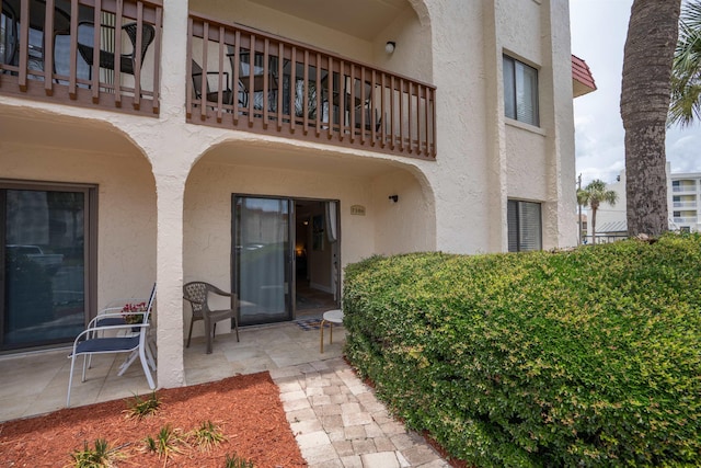 view of exterior entry featuring a patio area and a balcony