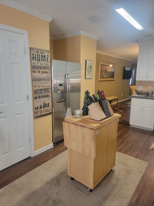 kitchen featuring white cabinets, stainless steel fridge, dark wood finished floors, a center island, and visible vents