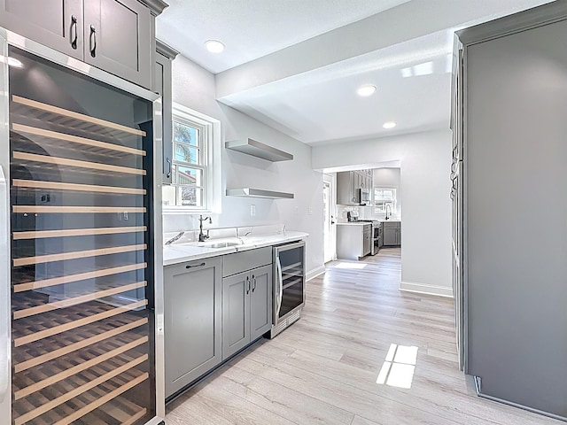 307 Minorca Ave, Saint Augustine, FL 32080 - kitchen with wine cooler, gray cabinetry, light wood-type flooring, and stainless steel gas range oven