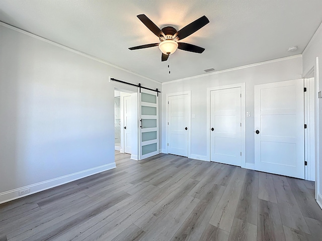 307 Minorca Ave, Saint Augustine, FL 32080 - unfurnished bedroom with two closets, crown molding, a barn door, and wood finished floors