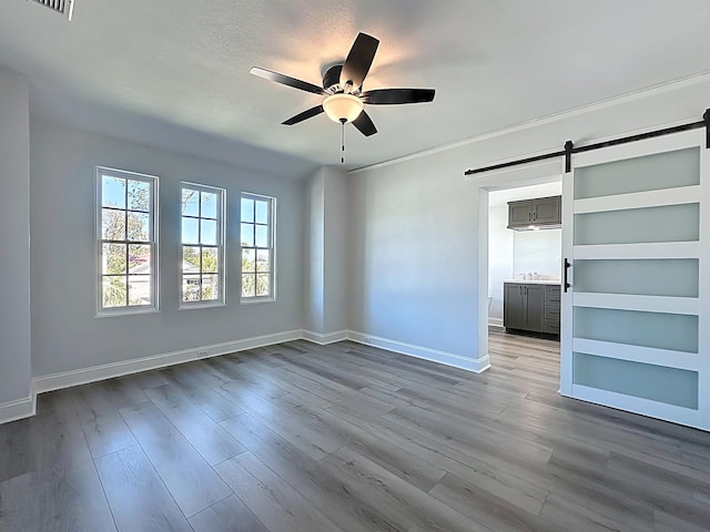 307 Minorca Ave, Saint Augustine, FL 32080 - unfurnished room featuring a barn door, a ceiling fan, dark wood-type flooring, and baseboards