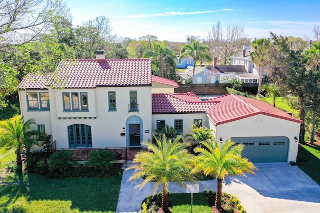 mediterranean / spanish home with stucco siding, a tiled roof, a chimney, and a garage